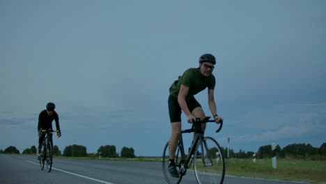 Zwei-Radfahrer-Fahren-Abends-Nach-Sonnenuntergang-Auf-Der-Straße.-Frühmorgens-Trainieren-Radfahrer-Mit-Helmen